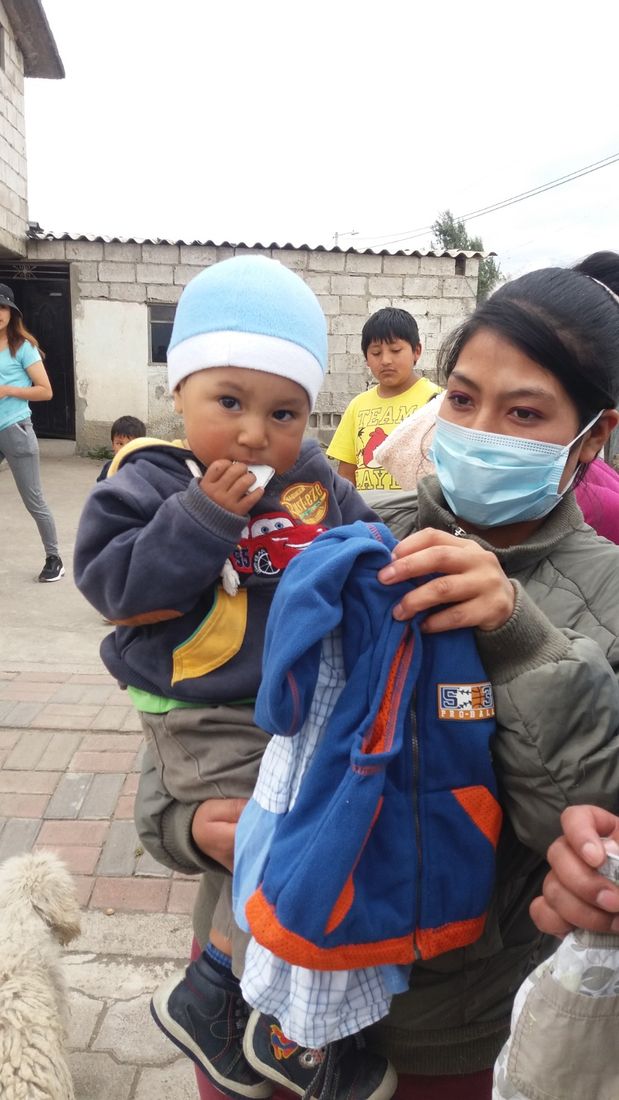 Madre recibiendo ropa donada para su hijo en una jornada solidaria de FESPE